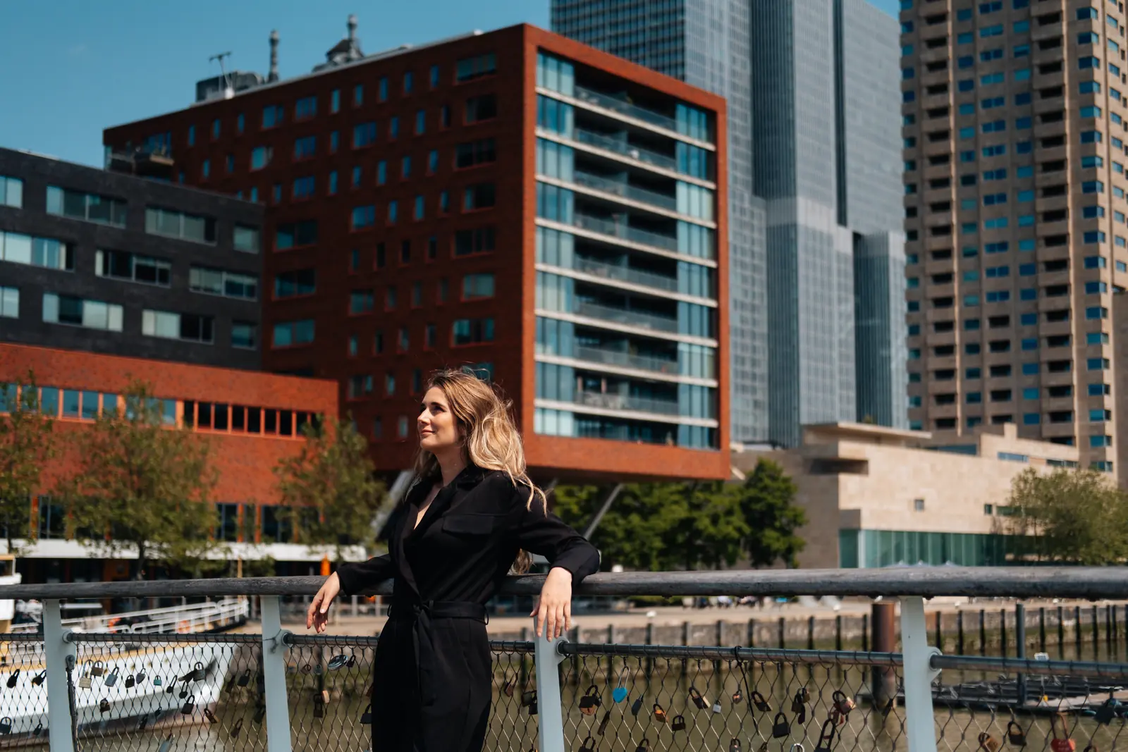 Carlijn Bekker, social media strateeg, aan een reling met de skyline van Rotterdam