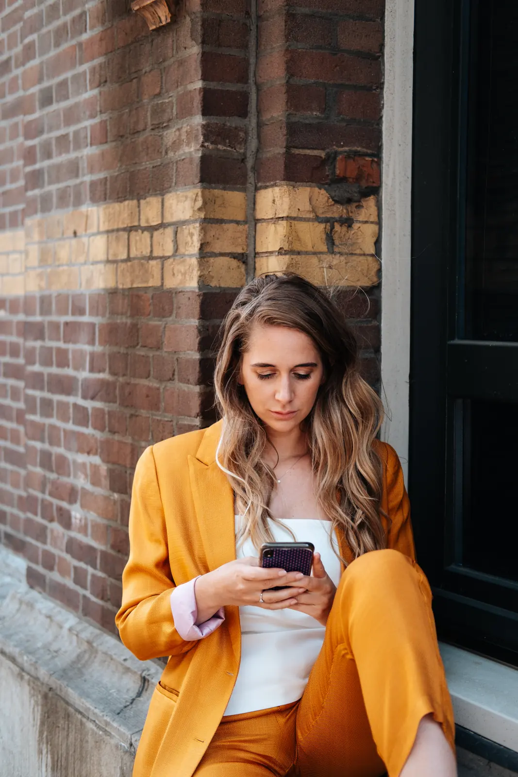 Carlijn Bekker, social media strateeg, in een oranje pak met haar telefoon
